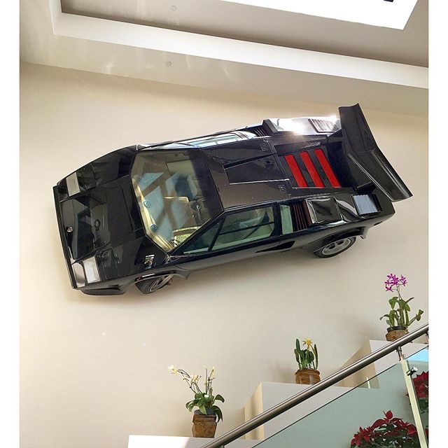 How's that for wall art? A Lamborghini Countach, sans V12, mounted to the wall above the stairs at the entrance to a home I visited today. The V12 is in the garage, under a glass table top, and it runs. With open headers. #